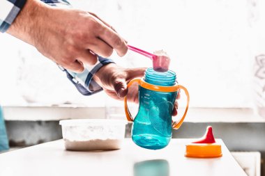 Bebek için hazırlık süt. Baba süt çocuğu için hazırlar. Baba rolü. Kavramı bir yaşam tarzı. Adam yapay süt, toz şişe içine dökülen. Bir çocuk için yapay süt.