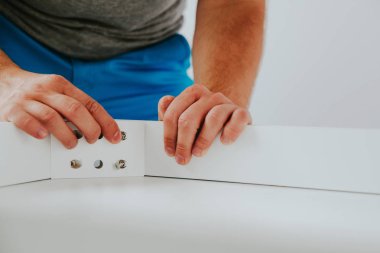 Kendinden montajlı mobilya. Adam ahşap bir mobilya parçası toplanır. Bunu kendiniz evde, DIY. Adam köşeye vida berbat. Tesisatçı'nın çalışmalarının bir önizleme.