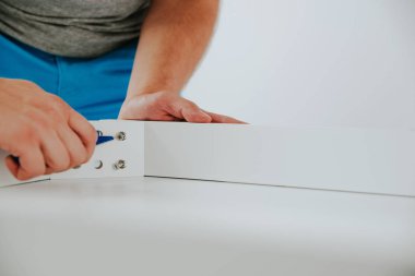 Kendinden montajlı mobilya. Adam ahşap bir mobilya parçası toplanır. Bunu kendiniz evde, DIY. Adam bir vida bir tornavida ile dalga geçiyor. Tesisatçı'nın çalışmalarının bir önizleme.