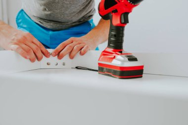 Kendinden montajlı mobilya. Adam ahşap bir mobilya parçası toplanır. Bunu kendiniz evde, DIY. Kablosuz bir vida vidalama bir adam. Tesisatçı'nın çalışmalarının bir önizleme.