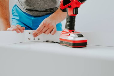 Kendinden montajlı mobilya. Adam ahşap bir mobilya parçası toplanır. Bunu kendiniz evde, DIY. Kablosuz bir vida vidalama bir adam. Tesisatçı'nın çalışmalarının bir önizleme.