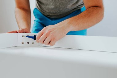 Kendinden montajlı mobilya. Adam ahşap bir mobilya parçası toplanır. Bunu kendiniz evde, DIY. Adam bir vida bir tornavida ile dalga geçiyor. Tesisatçı'nın çalışmalarının bir önizleme.