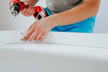 Kendinden montajlı mobilya. Adam ahşap bir mobilya parçası toplanır. Bunu kendiniz evde, DIY. Adam ahşap vidalar vidalı. Tesisatçı'nın çalışmalarının bir önizleme.