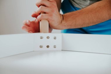 Kendinden montajlı mobilya. Adam ahşap bir mobilya parçası toplanır. Bunu kendiniz evde, DIY. Adam ahşap unsurları birleştirir. Tesisatçı'nın çalışmalarının bir önizleme.