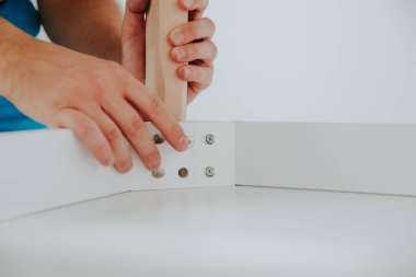 Kendinden montajlı mobilya. Adam ahşap bir mobilya parçası toplanır. Bunu kendiniz evde, DIY. Adam ahşap unsurları birleştirir. Tesisatçı'nın çalışmalarının bir önizleme.