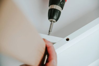 Kendinden montajlı mobilya. Adam ahşap bir mobilya parçası toplanır. Bunu kendiniz evde, DIY. Adam bir kablosuz kullanarak ahşap öğelerini birleştirir. Tesisatçısı çalışma.