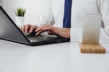 Ofis işi. Bir adam bir dizüstü bilgisayar önünde oturan ve çalışıyor. Mavi bir kravat da giyinmiş bir çalışma iş adamı önden görünümü.