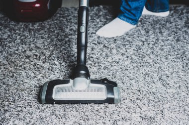 Vakumlama fayans mutfak, banyo. Adam gri elektrikli süpürge kullanarak mutfakta yerde toz.