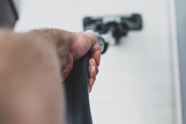 Vakumlama fayans mutfak, banyo. Adam gri elektrikli süpürge kullanarak mutfakta yerde toz.