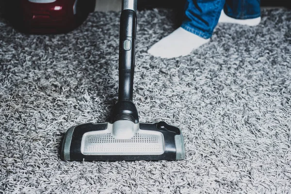 Vacuuming tiles in the kitchen, bathroom. The man dusts the floor in the kitchen, using a gray vacuum cleaner.