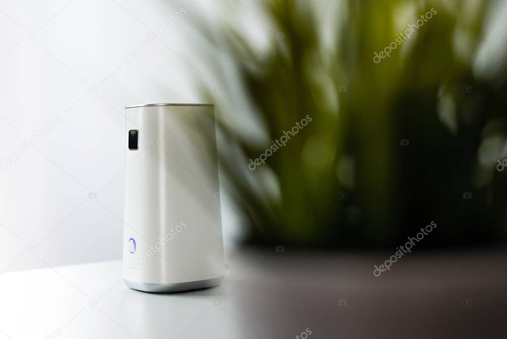 Ionizer stands on a white shelf on a white background. Air purifier at work, taking care of the comfort of residents, employees in the office. Getting rid of dust, smog, viruses, fungi from the air.