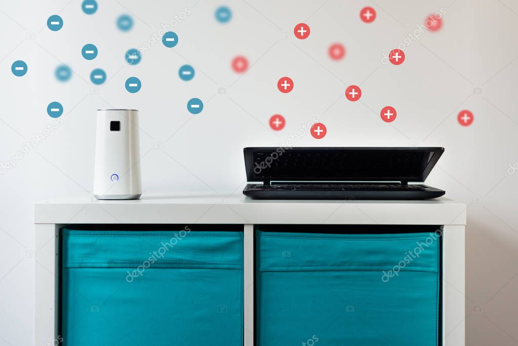 Ionizer stands on a white shelf on a white background. Air purifier during operation. A ionizer that releases negative ions and a laptop that releases positive ions. Caring for clean air at home.