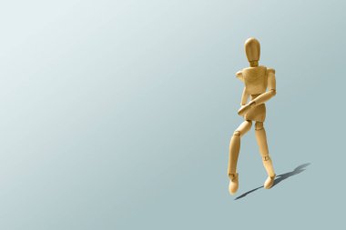 Ahşap manken çalışan bir poz. Ahşap model kaçıyor. Çalışan, eğitim sabah. Koşu. Ahşap figürü pastel mavi bir arka plan üzerinde çalışır. Bir fiziksel durumu kavram için bakım.