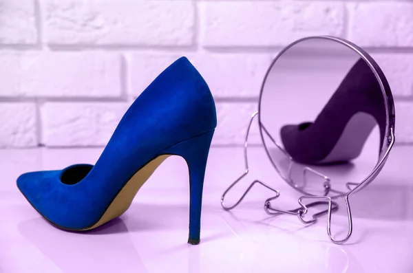 High heels blue. One high heel shoe is reflected in the mirror. The concept of fashion, modernity. Online store, shoe shopping. The shoe is viewed in the mirror, high heel. A bright, white background.