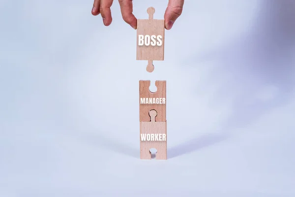 Hand holding a wooden jigsaw puzzle with blank space. There is a matching puzzle next to it. Career concept from employee to boss.
