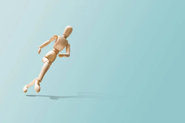 木模在逃 木制人体模型以跑步的姿势 木材的身影在柔和的蓝色背景上运行 关心身体状况的概念 — 图库照片
