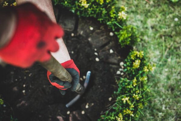 Работа в саду. Мужчина копает в саду, делает саженцы. Садовник, одетый в брюки и рабочую обувь, делает свою работу. Вид сверху на человека, работающего с сапогом в земле
.
