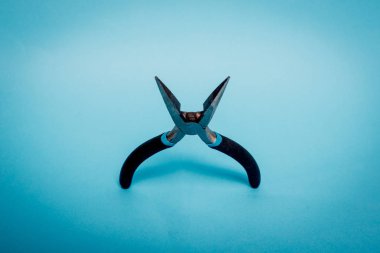 Kerpeten Siyah saplı bir yeşil, Turkuaz pastel arka plan üzerinde yalan. Üstten görünüm açık pense. Gerekli iş araçları her evde bir görüntü. Minimalizm kavramı.