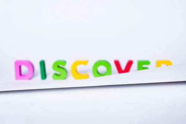 DISCOVER word made of colorful letters. Partially covered DISCOVER sign made of wooden letters. The concept of discovering new things, traveling and learning about new places.