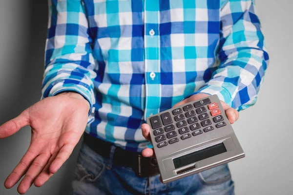 Man is showing the calculator with the number zero and the folded hand. Act of helplessness, powerlessness. The man can not explain the bad financial situation. Business concept, financial problems.