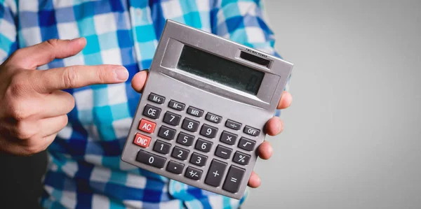 Man dressed in a shirt, businessman counts on a calculator. Financial and business growth concept. Man's finger clicks on the buttons on the gray calculator, the calculator shows the number zero.