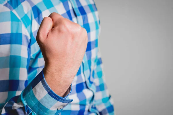 Showing fists in the act of victory. A man, a businessman shows a sign of a clenched fist up. Business concept, contentment, happiness. Isolated on a gray background.