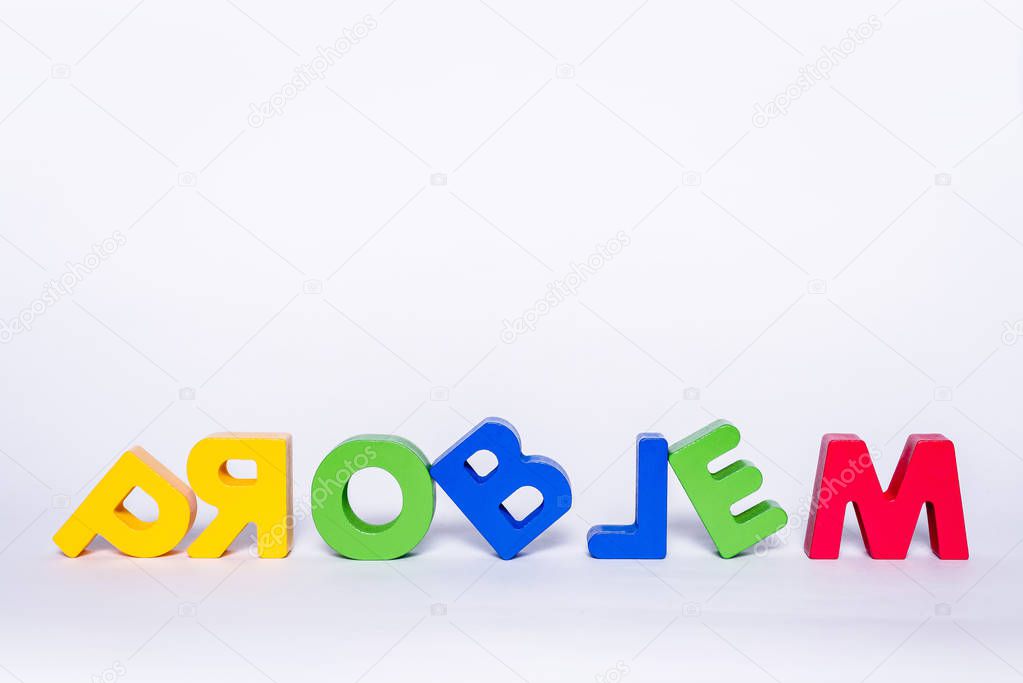 Word PROBLEM on an isolated white background. Lettering PROBLEM made up of wooden and colorful letters with scattered letters. Concept of problem solving, lifestyle.