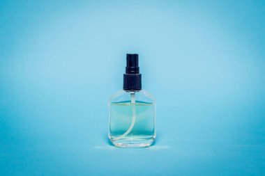 Pastel bir arka plan üzerinde izole şeffaf parfüm şişesi. Tuvalet su şişesi siyah bir fiş ile.