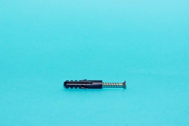Pastel bir arka plan üzerinde siyah bir peg içine metal vida berbat. Minimalizm kavramı.