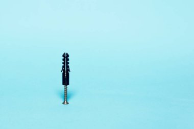 Pastel mavi arka plan üzerinde siyah bir peg içine metal vida berbat. Minimalizm kavramı.