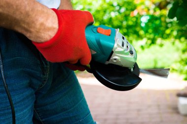 Adam bir öğütücü ile biçme'nın bıçak bileme. Bir açı değirmeni netlik için kesme kullanarak. Bahçede üretim tesisi çalışır.