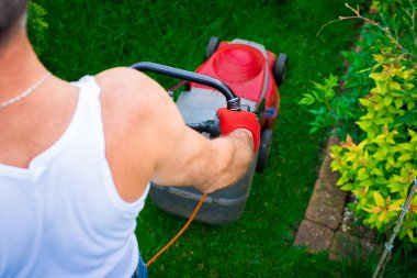 Çim biçme üzerinde yukarıdan. Bahçıvan çim ile kırmızı bir elektrik biçme mows. Bahçe, bahar temizliği işe. Bahçe ve çim bakımı.