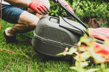 Çim biçme. Bahçıvan çim ile kırmızı bir elektrik biçme mows. Bahçe, bahar temizliği işe. Bahçe ve çim bakımı.