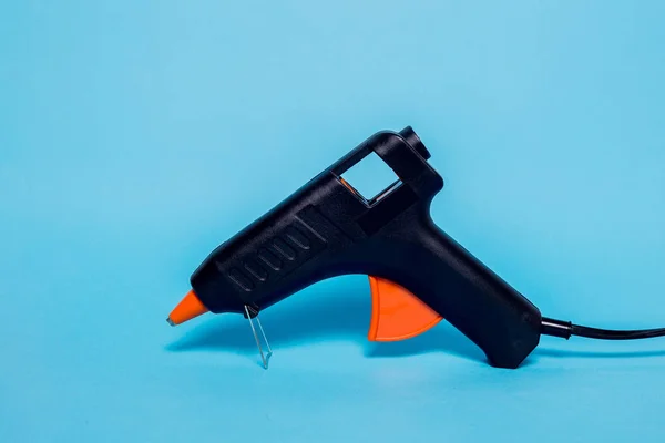 Svart Limpistol Med Orange Handtag Blå Pastell Bakgrund Begreppet Limning — Stockfoto