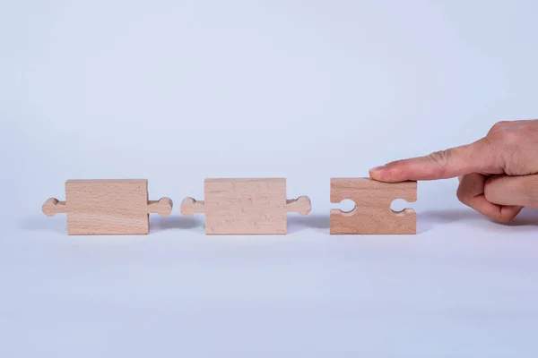 Hand holding a wooden jigsaw puzzle with blank space. There is a matching puzzle next to it. The concept of solving problems, all problems can be solved, connection.