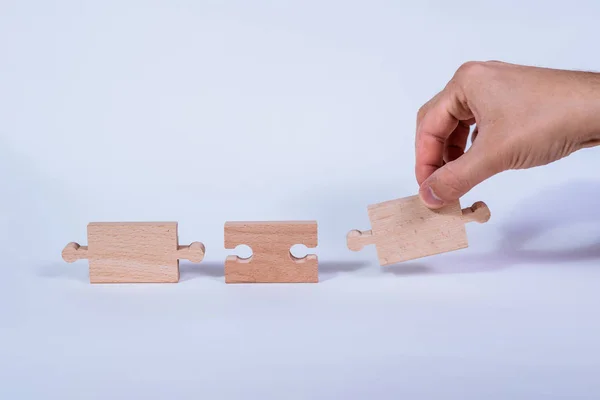 Hand holding a wooden jigsaw puzzle with blank space. There is a matching puzzle next to it. The concept of solving problems, all problems can be solved, connection.