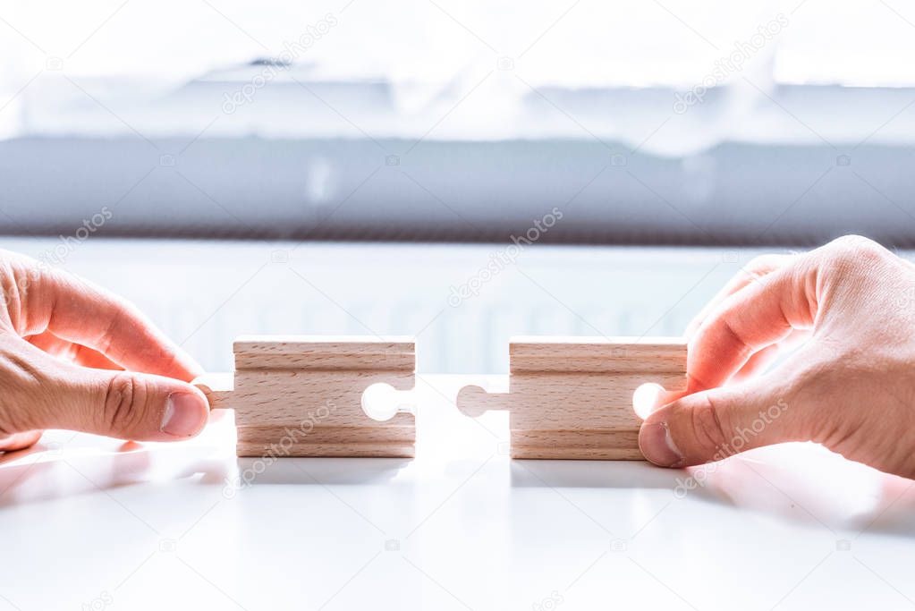 Hand holding a wooden jigsaw puzzle with blank space. There is a matching puzzle next to it. The concept of solving problems, all problems can be solved, connection.