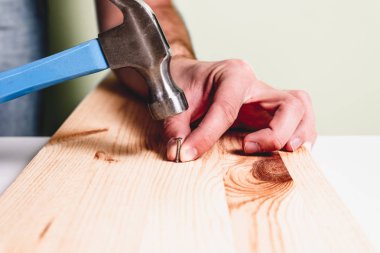 Ahşap plaka çivi çekiç. Tadilat, ev kavramı. Adam mavi çekiç çivi diğer elinde tutan, elinde tutuyor. Tamirci, DIY.