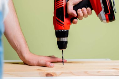 Ahşap plaka delme. Adam bir tornavida ya da matkap elinde tutuyor. Bir matkapla bir matkap kullanarak duvarda bir delik matkap. Ev işleri, Ev Tadilat, ev kavramı.