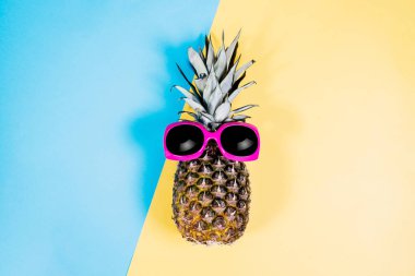 Moda ananas. Yaz rengi. Tropikal meyve güneş gözlüklü. Minimalist tarzı. Yaratıcı sanat kavramı. Pembe, sarı ve mavi pastel renkler üzerinde ananas.