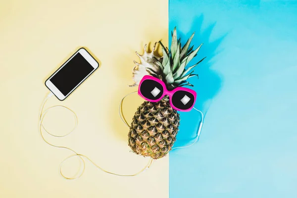菠萝和太阳镜 配有耳机和手机 夏天来了概念 简约的风格 简约的摄影风格 粉色和蓝色柔和的颜色 — 图库照片