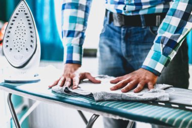 Adam evde elbise Ütü. Baba eve görevleri gerçekleştirir, çocuğun giysileri Irons. Bir adam bir kadının evde rolü. Adam Ütü forması ile mavi demir buharlı ütü masası.