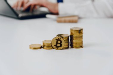 Altın sikke masanın üzerinde. Beyaz masaya vardır bitcoin altın sikke, bir adam inşaat arka planda. Cryptocurrencies üzerinde kazanç finansal büyüme kavramı bitcoin artırır.