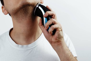 Tıraş elektrikli tıraş makinesi ile. Adam bir tıraş makinesi elinde tutuyor. Yüz saç, sakal, bıyık kurtulmak keserek kavramı. Dikkat çekici bir adam. Adam gitmek için hazırlık.