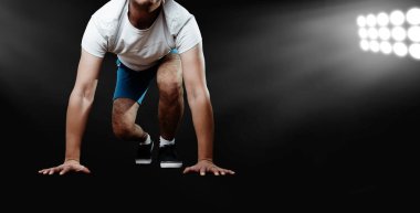 Adam bir crouch yere dokunmadan eller ile kalıyor. Rekabet Spot için hazır başlangıç satırında crouching koşucu. Adam bir esmer, siyah arka plan üzerinde kalkışa hazır.