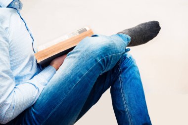 Kitap tarama kitap okumak. Bir kitap elinde tutan duvara karşı mavi bir gömlek giymiş bir adam oturuyor. Öğrenme bilgi yapışmasını sınav öncesi. Merak. Kitap okuma kavramı.