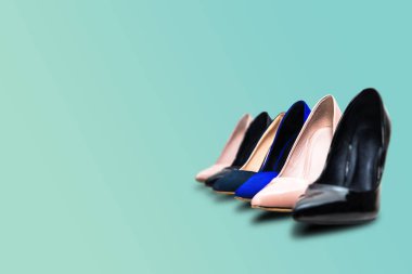 Pastel yeşil bir arka plan üzerinde yüksek topuklu ayakkabı. Moda kavramı, podyum. Online mağaza, moda mağazası, ayakkabı satışı. Yüksek topuk yanında ikinci bir yatıyor. Ayakkabı kadınlar için.