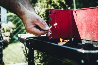 Aydınlatma, mangal yakmak. Bir adam bir Barbekü kibritle başlatmıştır. Grill'de aile ile birlikte vakit. Sosyal toplantılar, arkadaşlar. Odun ve kömür ile kırmızı kiremit.
