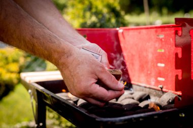 Aydınlatma, mangal yakmak. Bir adam bir Barbekü kibritle başlatmıştır. Grill'de aile ile birlikte vakit. Sosyal toplantılar, arkadaşlar. Odun ve kömür ile kırmızı kiremit.
