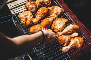 Tavuk ızgara döşeme. Adam ızgarada tavuk budu koyar. Grill'de aile ile birlikte vakit. Sosyal toplantılar, arkadaşlar. Odun ve kömür ile kırmızı kiremit.